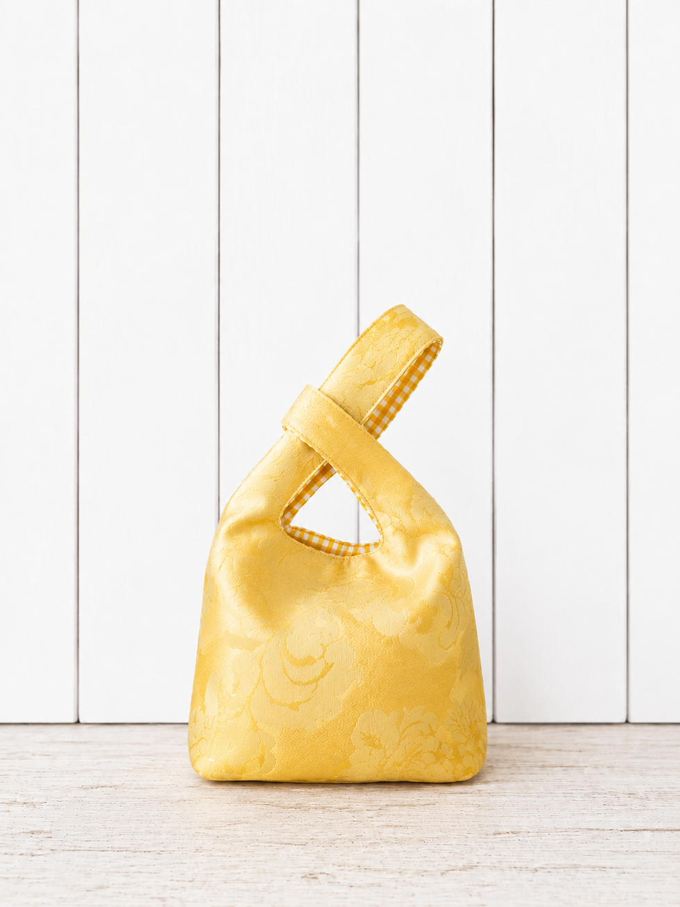 Sac Knot Bag jaune fait main en tissu satiné à motifs avec détails vichy jaune et blanc.