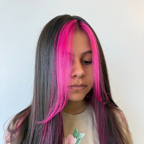 Long dark hair with vibrant hot pink money piece framing the face and hidden underlights. This trendy hybrid style is available in Glendale Heights.