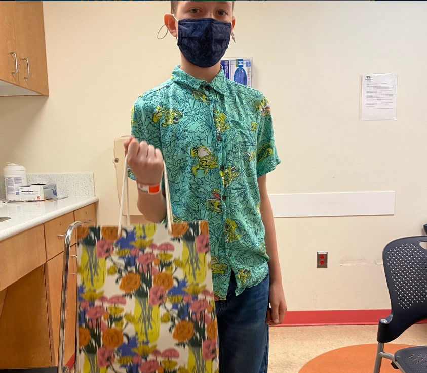 Max Pound holding donation gift bags for pediatric cancer patients at Children’s National Hospital. Through The Max Pound Foundation, Max raised over $10,000 to support children battling pediatric brain cancer and other pediatric cancers, advancing patient support and awareness aligned with the Pediatric Neuro-Oncology Consortium (PNOC) and pediatric neuro-oncology research initiatives.