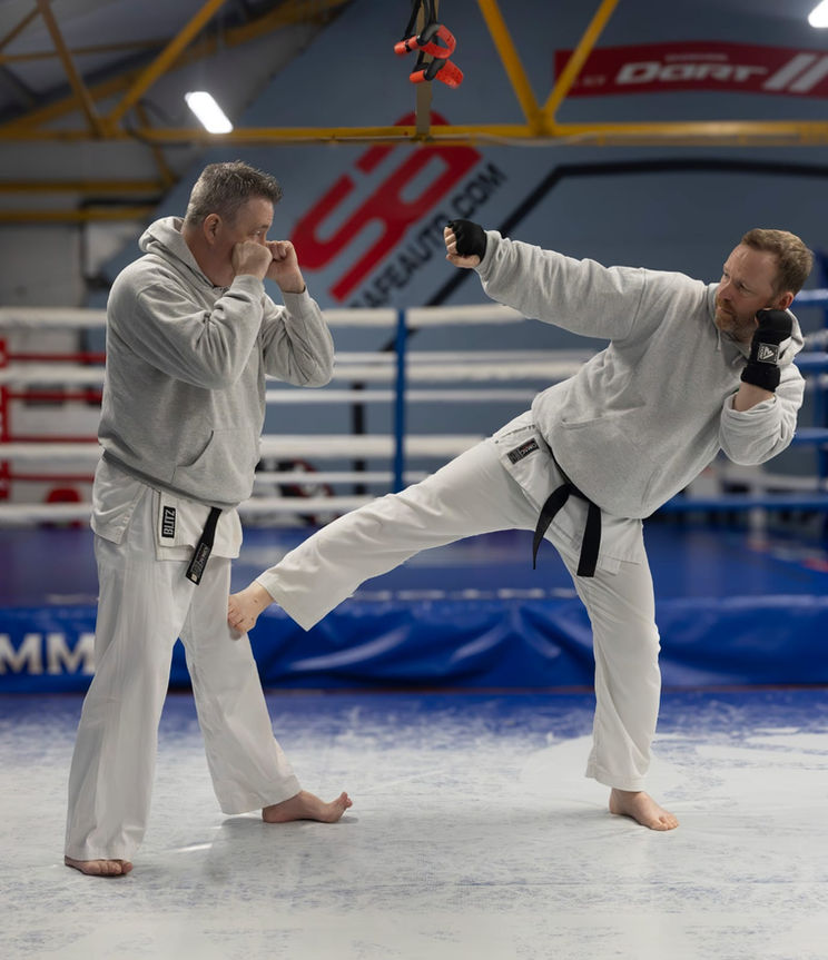 Two Jitsugi karate instructors demonstrating a side kick, in sports hall in Clydebank, Glasgow