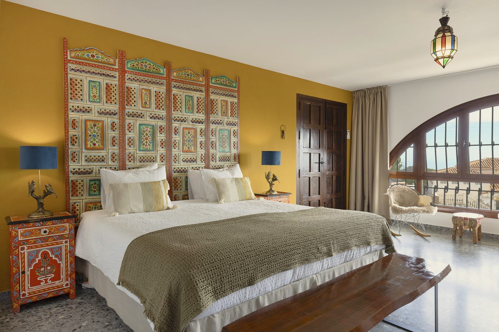 Pilea Suite: bedroom with ornate headboard and arched window