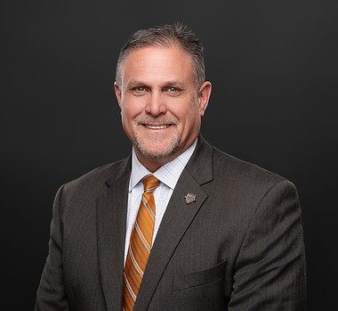 Man in dark suit smiling at camera in his headshot. By makana photography, a product, headshot and branding photographer in PInehurst, Southern Pines, Aberdeen and Sanford
