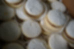 Close-up of Alfajores stuffed with dulce de leche or arequipe, dusted with powdered sugar in paper cups.