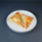 Two golden-baked puff pastries with dulce de leche and cheese filling on a plate.