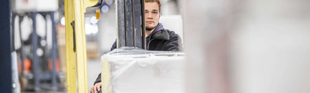 Logistik Mitarbeiter stapelt Paletten mit dem Gabelstapler