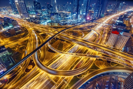 High-resolution aerial-style illustration of a multi-lane coastal highway and causeway under construction, stretching from Abu Dhabi’s mainland to a ferry terminal island, surrounded by desert and sea, representing the UAE’s West Link infrastructure project.