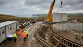 Concrete service reservoir under construction at a UK water utility site with crane lifting precast panels