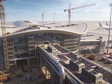 Airport terminal construction featuring advanced MEP systems installation, curved roof architecture, tower cranes, scaffolding, and aviation apron infrastructure, showcasing large-scale international airport redevelopment, complex electrical and mechanical engineering, and modern passenger terminal expansion projects.