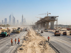 Major road corridor under construction in Dubai with earthworks and new bridge structure