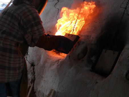 Gaunleted hands opening a hatch in an anagama kiln