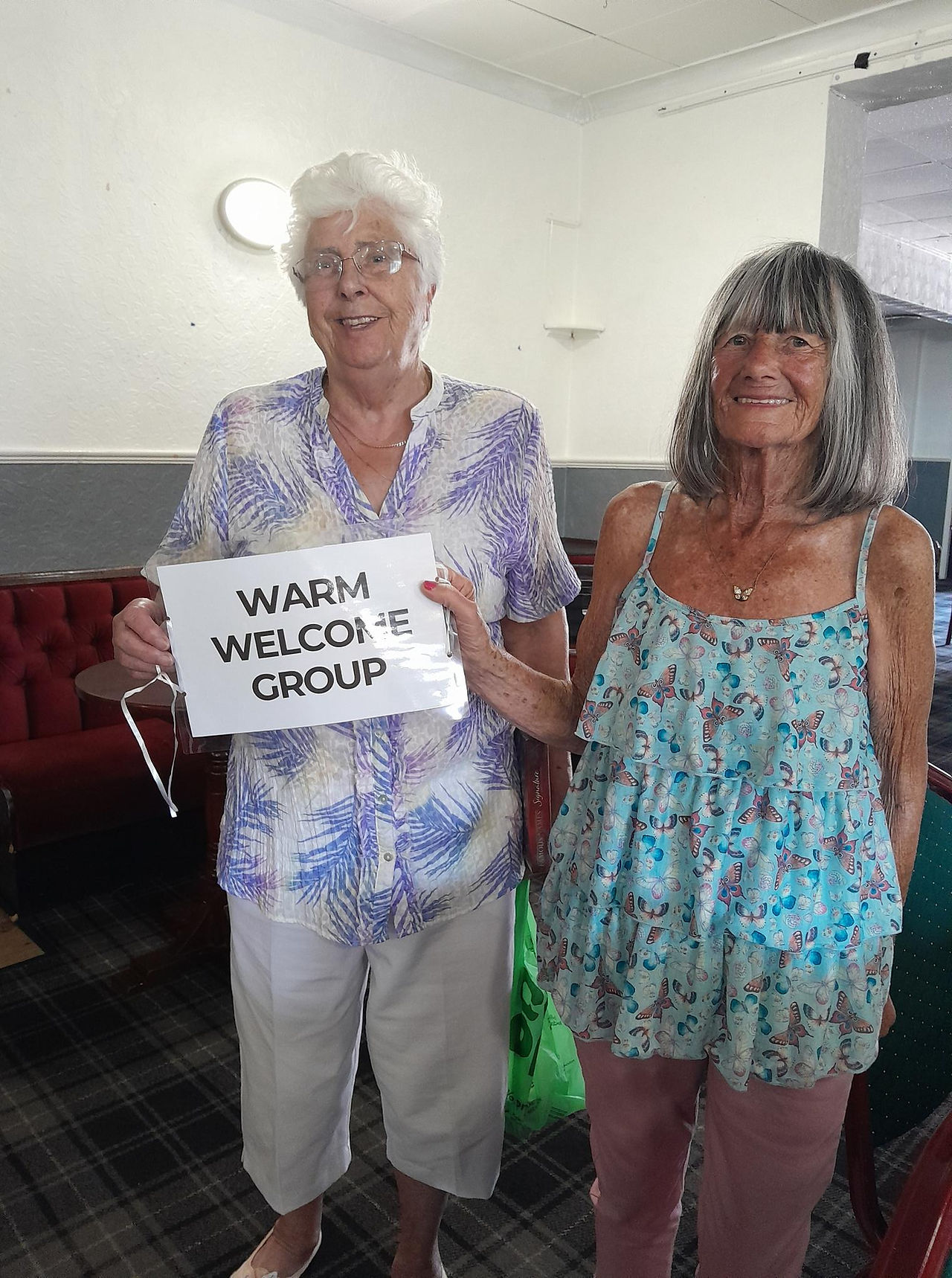 two warm welcome group members holding warm welcome group sign 