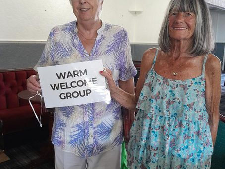 two elderly ladies holding up a warm welcome group sign