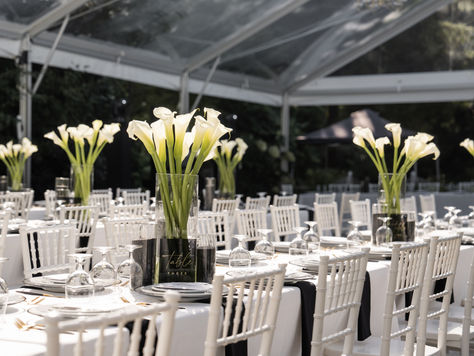 Sophisticated wedding reception at Fox Hollow Farm styled in black and white, showcasing tall vase centerpieces of calla lilies, crisp linens, and a refined, modern aesthetic.