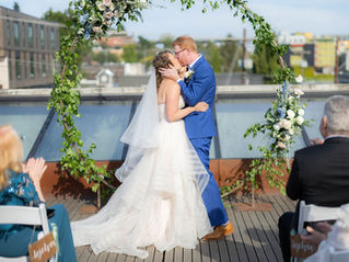 Bride and groom share their first kiss after saying “I do” beneath a round floral-covered arch at Fremont Foundry.