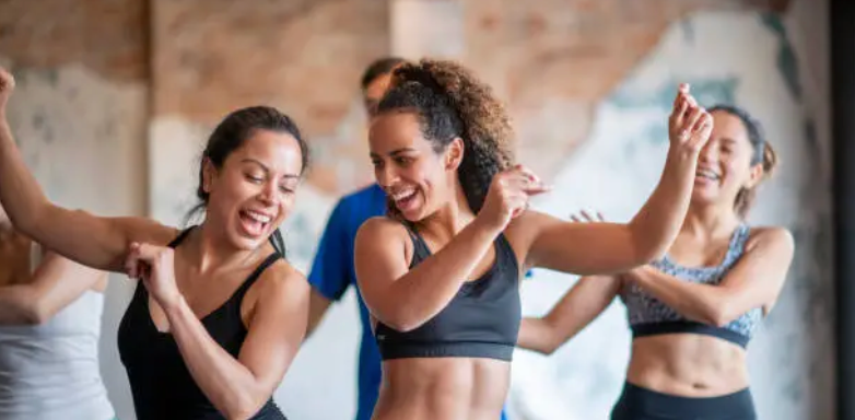 Women laughing and dancing in a fitness dance class.