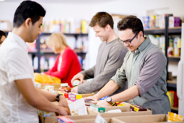 People sorting and packing food items into cardboard boxes.