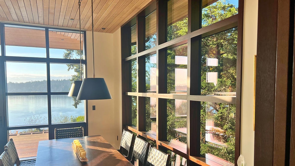 Wood-clad window wall in a Pacific Northwest waterfront home featuring dark aluminum exterior cladding and natural wood interior frames with lake views