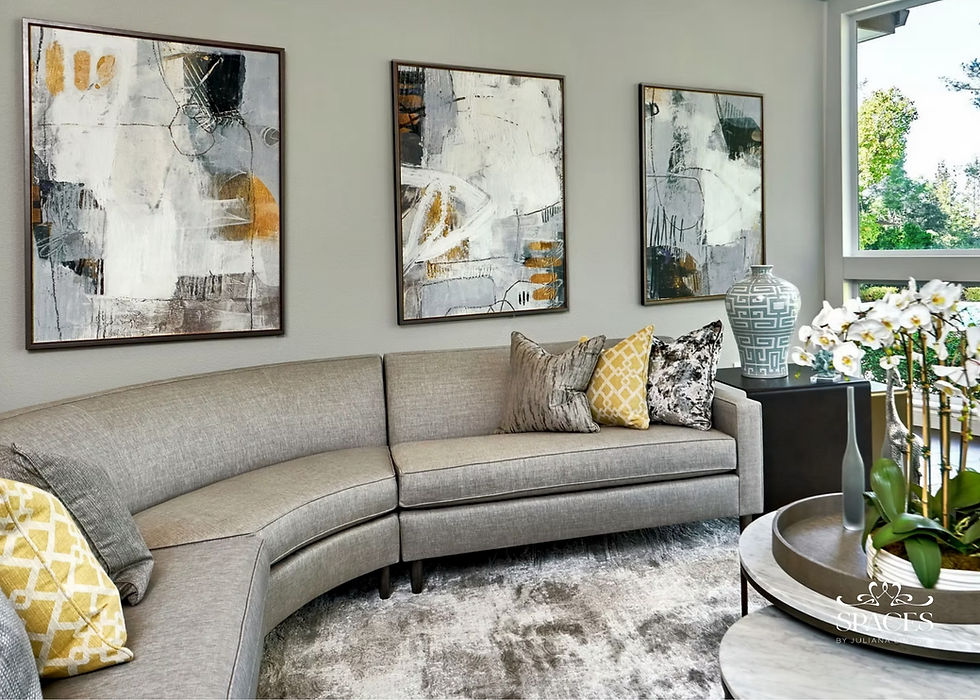 Contemporary living room with curved gray sofa, abstract art in gold frames, and floor-to-ceiling windows overlooking California landscape