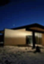 Snake River House exterior architecture showcasing smart glass technology and automated door systems in modern Wyoming mountain residence at night