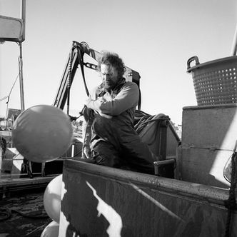 Schottischer Fischer auf Fischerboot Silver Star mit Boie, schwarz weiss Foto.