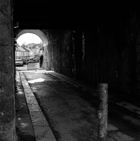 Blick durch eine dunkle Bahnunterführung ins St. Judes Quartier, Plymouth, England, schwarz weiss Foto.