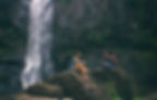 Pair talking next to a waterfall in the mountains