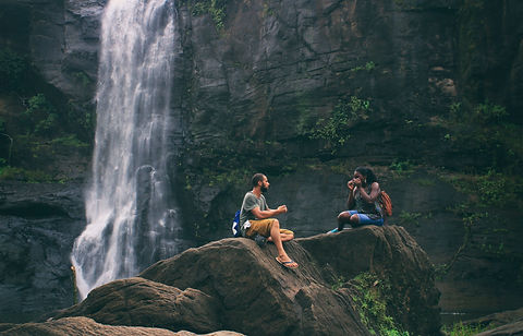 Pair talking next to a waterfall in the mountains
