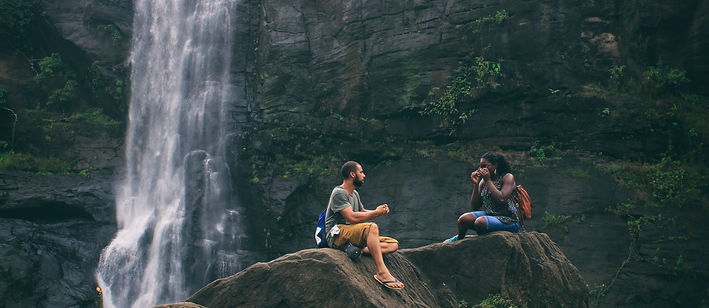 Pair talking next to a waterfall in the mountains