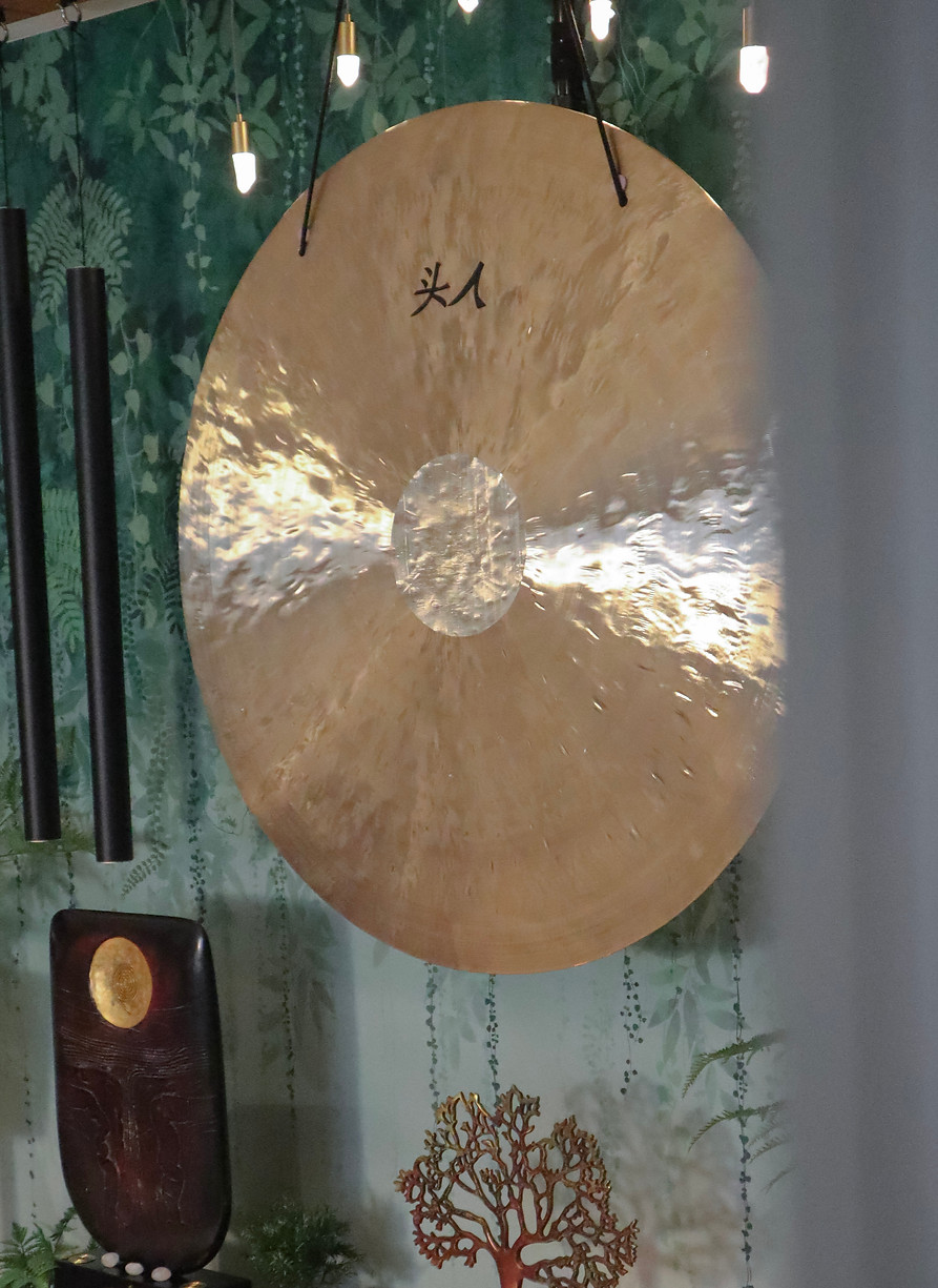 Sideways shot of a gold gong and black wind chimes in a studio.