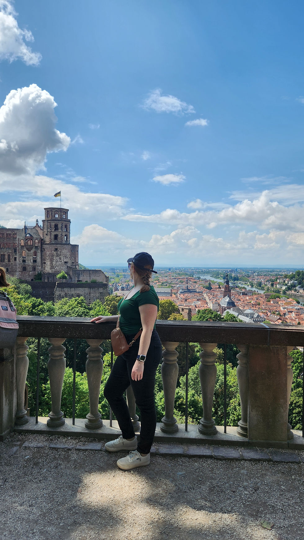 Stephanie standing near the banister overlooking Heidelberg Castle in Heidelberg, Germany. She is looking over her shoulder at the castle and away from the camera.