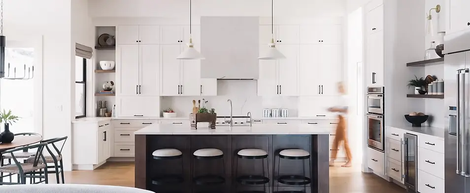 Luxury home staging and interior design in Portland, Lake Oswego, and West Linn. A modern open-concept kitchen featuring a black island, white shaker cabinets, gold pendant lighting, and high-end stainless steel appliances, designed by Greylyn Wayne.