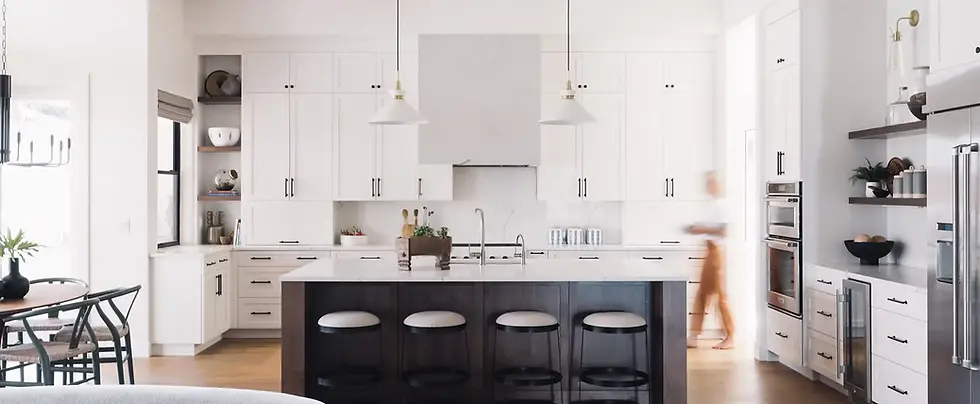 Luxury home staging and interior design in Portland, Lake Oswego, and West Linn. A modern open-concept kitchen featuring a black island, white shaker cabinets, gold pendant lighting, and high-end stainless steel appliances, designed by Greylyn Wayne.