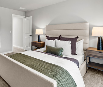 Staged bedroom by Greylyn Wayne featuring layered bedding, neutral tones, and modern interior design in Portland, Oregon