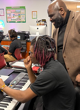 teacher and student in classroom playing a keyboard
