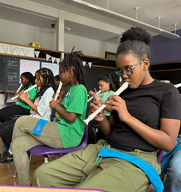 Kids sitting in chairs playing recorders