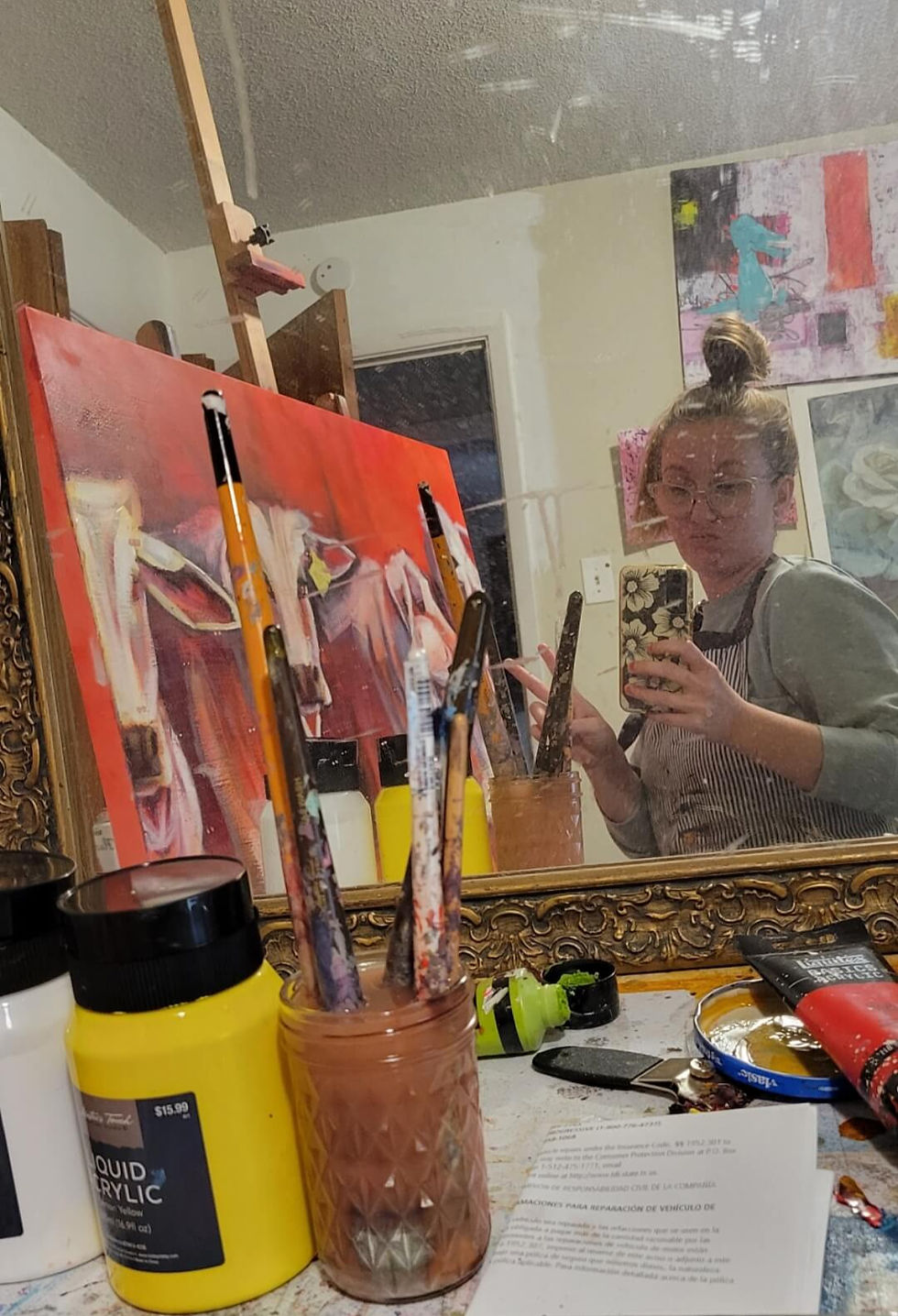 Mandi Murphy taking a mirror selfie with her materials and painting.