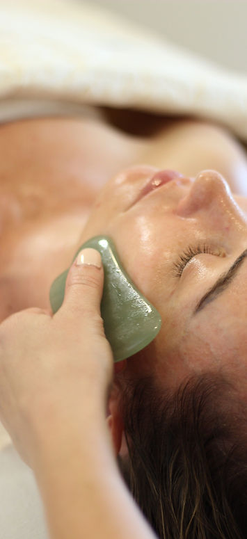 Client receiving gua sha with a green stone.