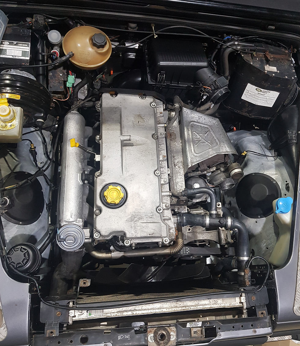 Top-down view of a Land Rover TD5 engine installed in a Defender engine bay, showing key components including turbocharger, intercooler, and fuel system during restoration.
