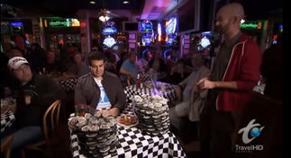 Adam Richman eating 18 dozen oysters at Acme Oyster House in New Orleans while a crowd cheers for him