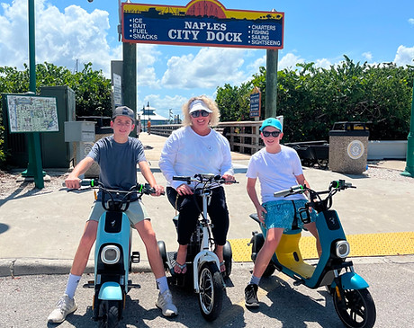 Family on electric mopeds at the Naples City Dock during a guided tour in Naples, Florida