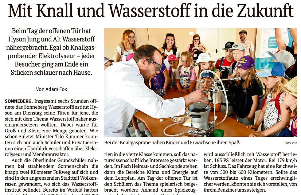 Ein Mann demonstriert Kindern in einem Laborversuch Wasserstoff. Die Kinder schauen gespannt zu. Im Hintergrund Erwachsene.