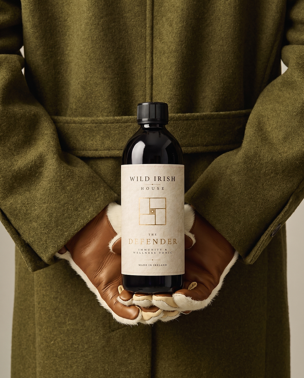 Defender tonic bottle held in hands wrapped in a deep green wool jacket