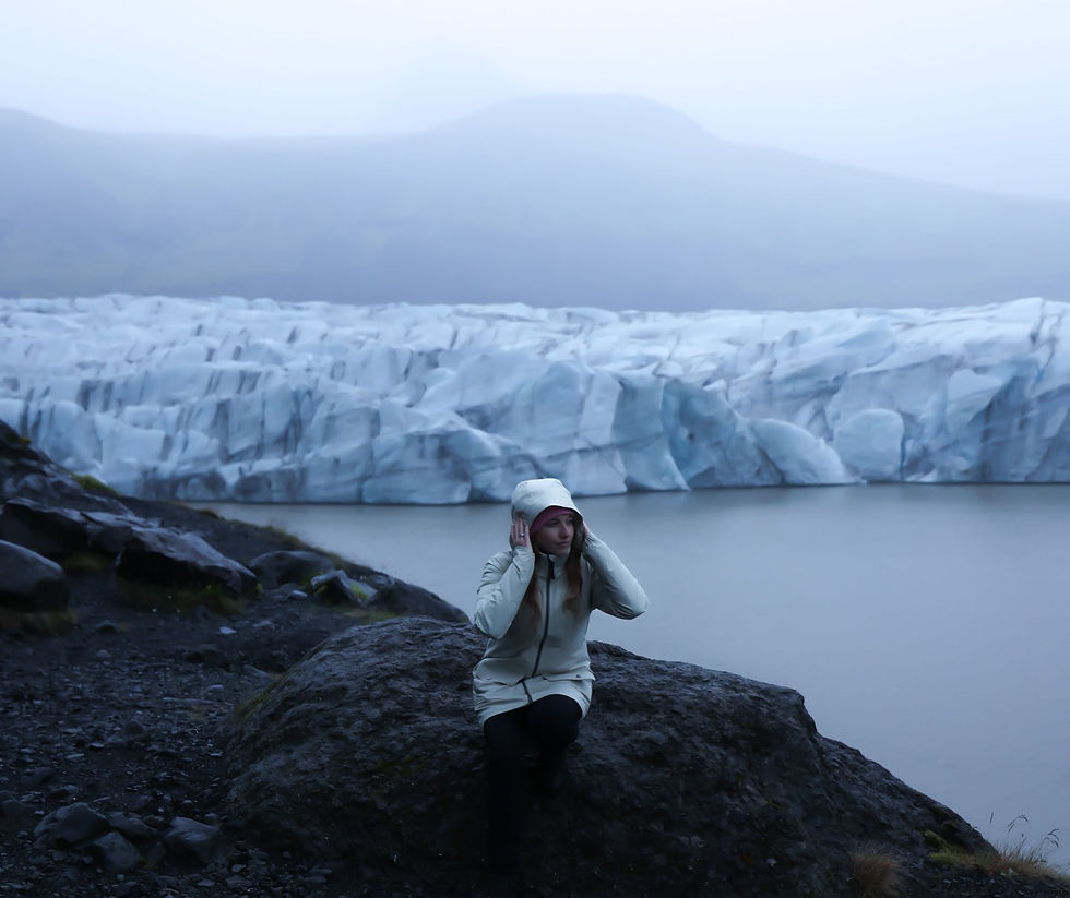 Svínafellsjökull glacier in Iceland with a girl sitting before the wall of ice staring at the fog covering the gletsjer on a moody midnight.