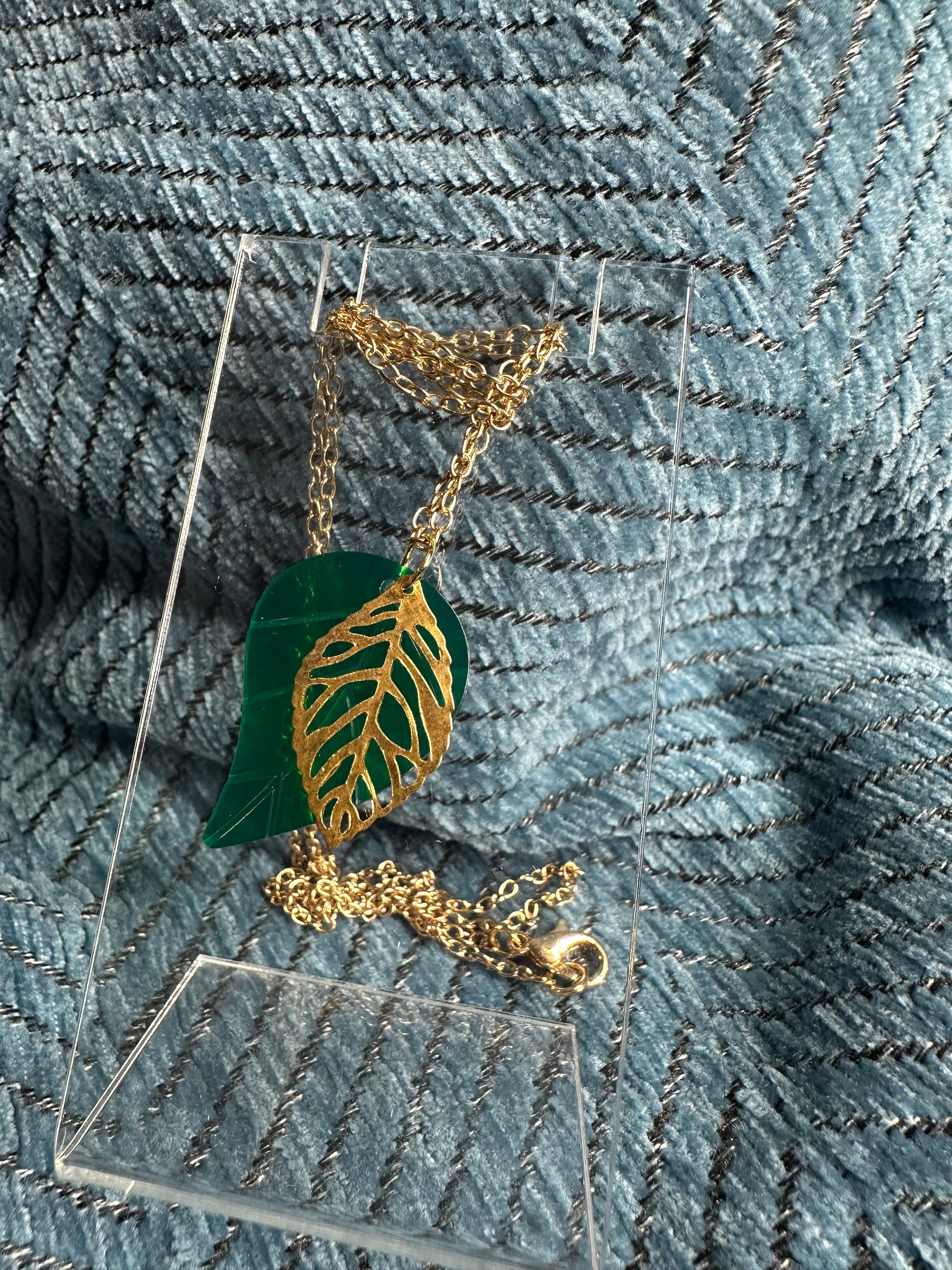 Nature-inspired gold necklace with a delicate green leaf silhouette pendant. 
