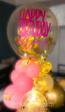 Balloon bouquet with large clear and gold confetti round balloon topper with hot pink Happy Birthday Makayla sticker on top balloon layers in pink, gold confetti with butterflies and LED light string