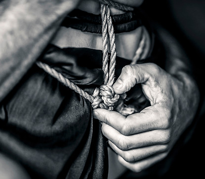 Close up van shibari knoop op een zijden achtergrond met mannenhand in zwart wit. 
