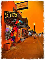 Orange sky is the backdrop of an art gallery awning in front of the Brian Scott Gallery.