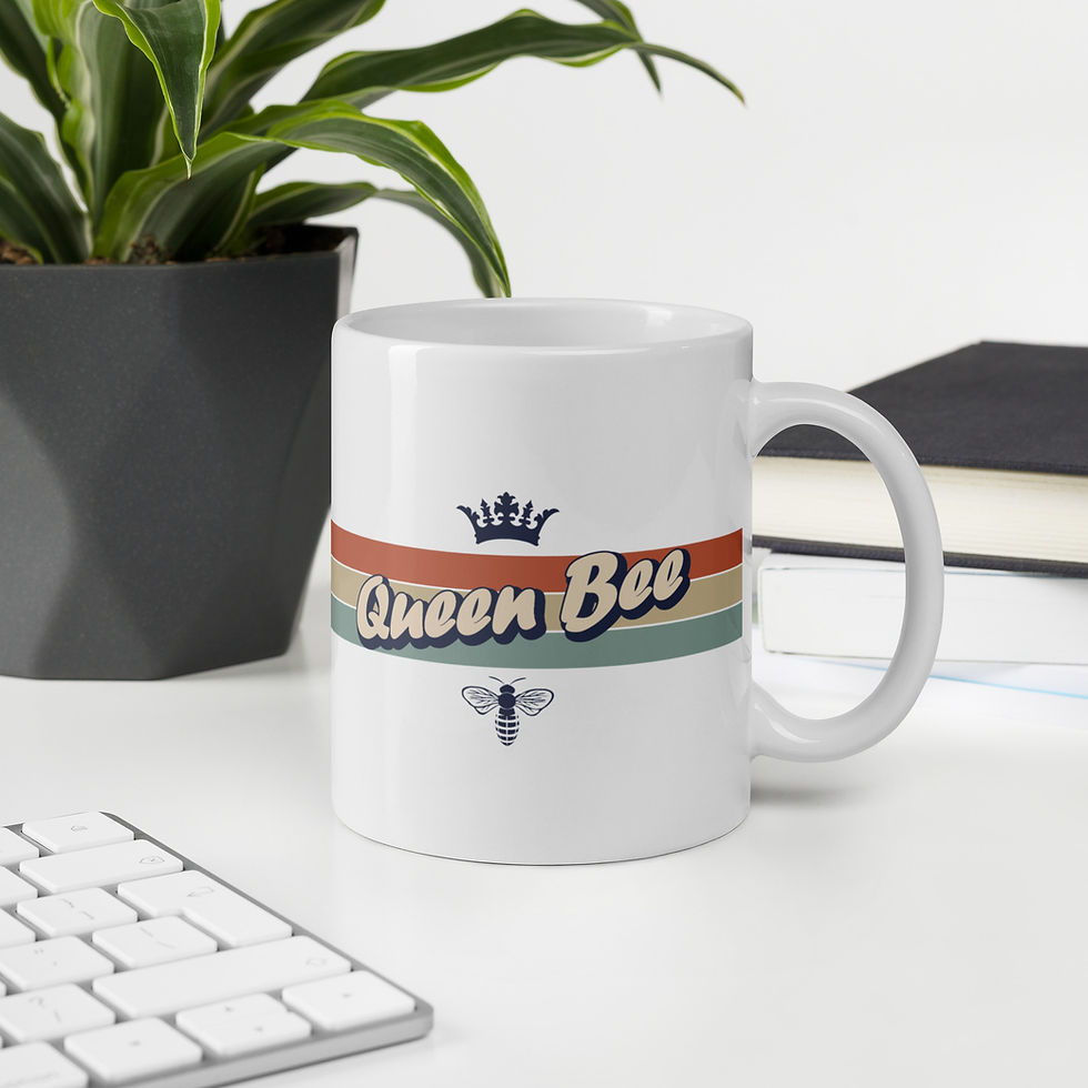 Thumbnail: glossy white ceramic mug with queen bee text, grey crown grey bee front view on a desk next to a potted plant