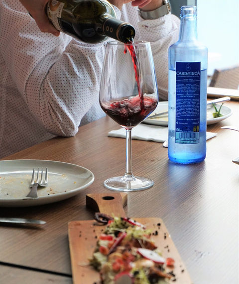 a waiter pours a glass of wine