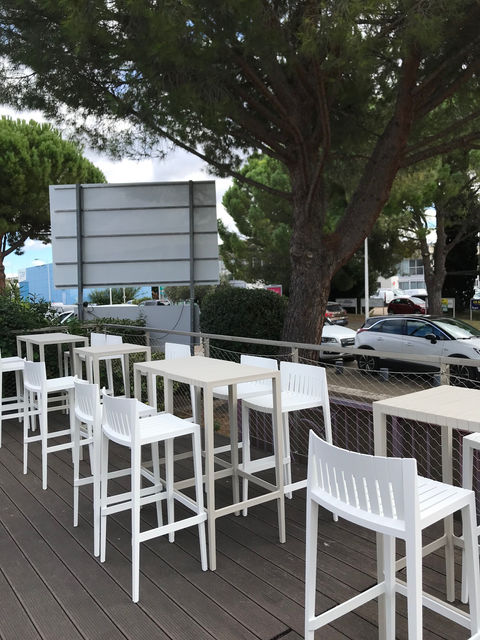 Spritz Stool Vondom 50x45x97cm sur terrasse de restaurant avec table haute, mobilier outdoor design et confortable.